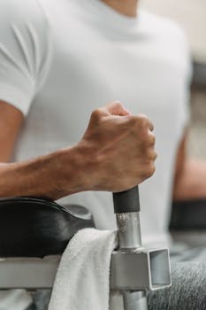 Crop unrecognizable muscular ethnic sportsman in white t shirt training in gym in daylight