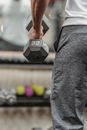 Crop man lifting dumbbell in gym