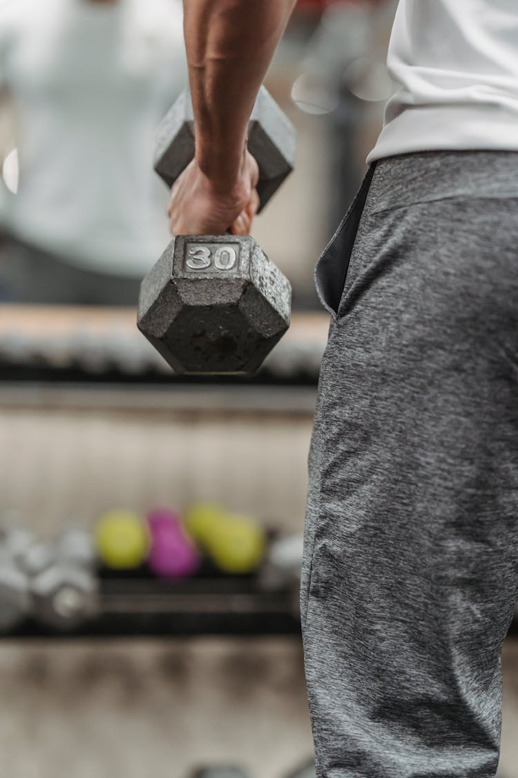 Crop Man Lifting Dumbbell In Gym