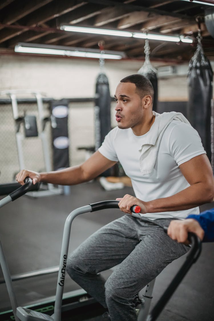 Motivated Ethnic Sportsman Exercising On Stationary Bicycle In Gym