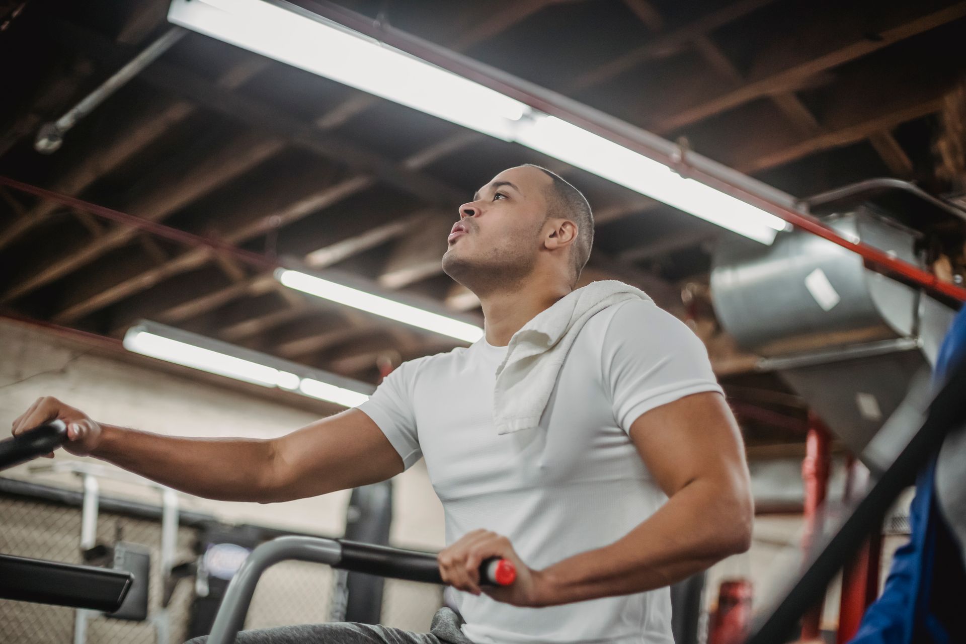 Strong ethnic sportsman exercising on stationary bike in gym