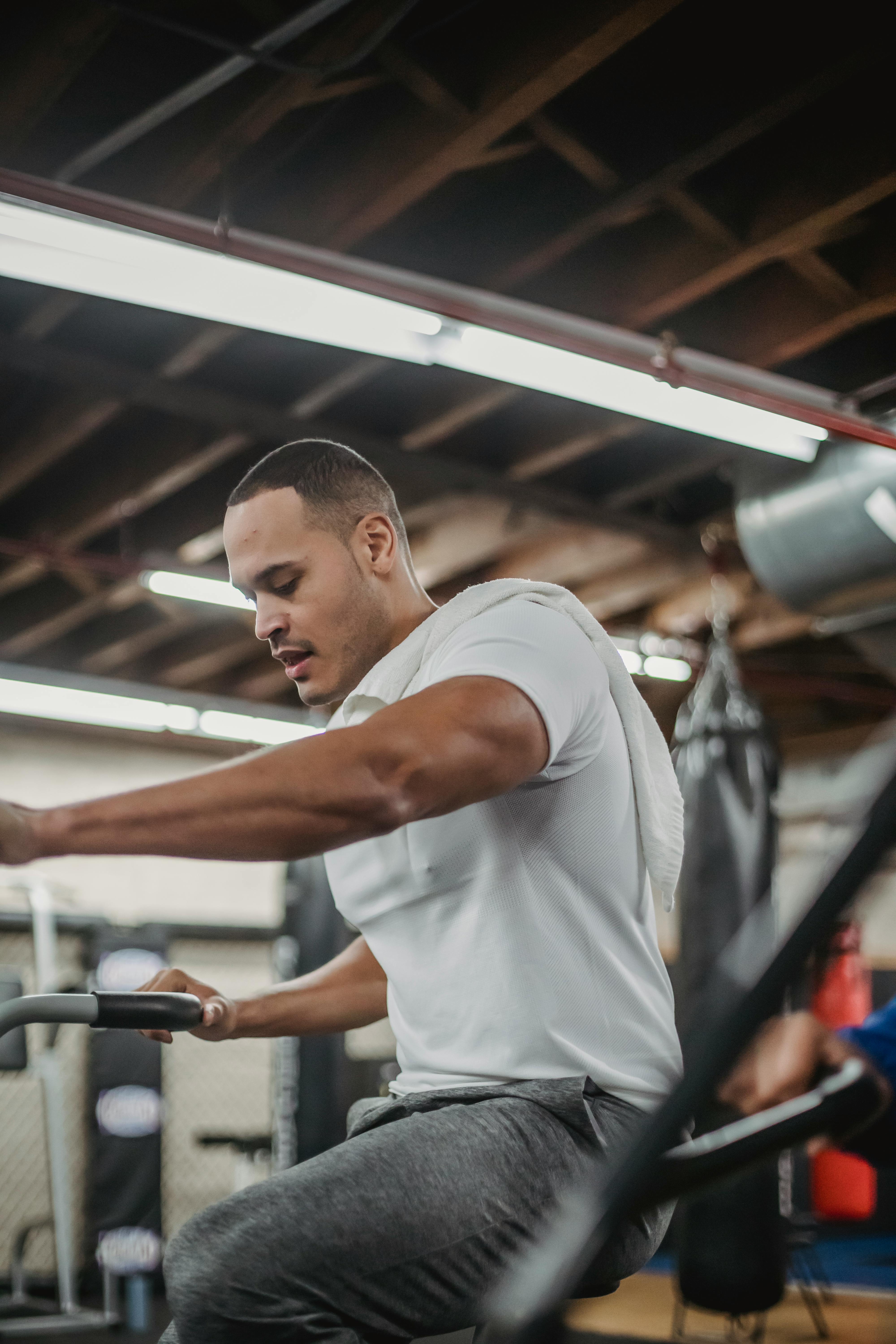 string ethnic sportsman cycling on stationary bike in gym