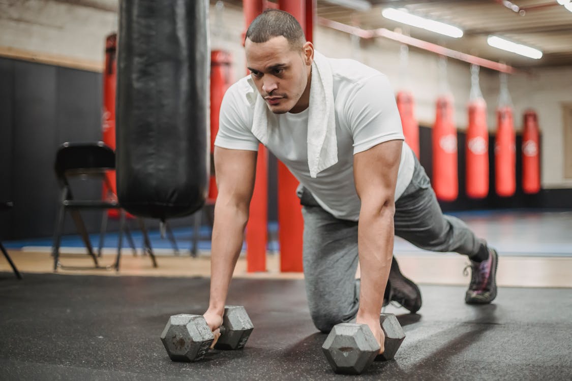 Free Determined ethnic sportsman doing pushups with dumbbells Stock Photo