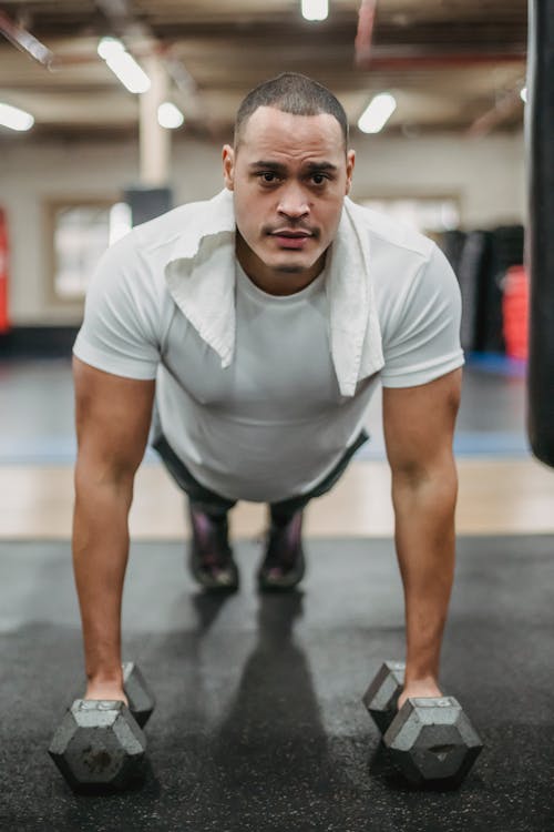 Strong sportsman performing push ups on dumbbells