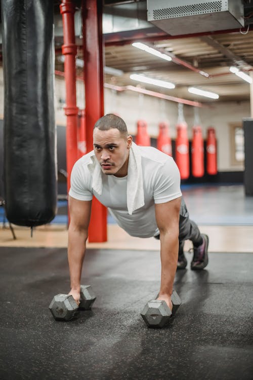 Free Dedicated ethnic sportsman doing push ups on dumbbells Stock Photo