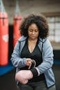 Plump black woman putting on boxing gloves in gym