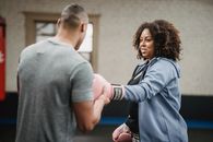 Smiling black woman preparing for boxing training with coach