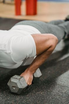 Crop unrecognizable male athlete in sportswear performing push up with dumbbells during workout in gym