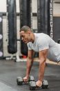 Muscular ethnic man doing plank with dumbbells in gym