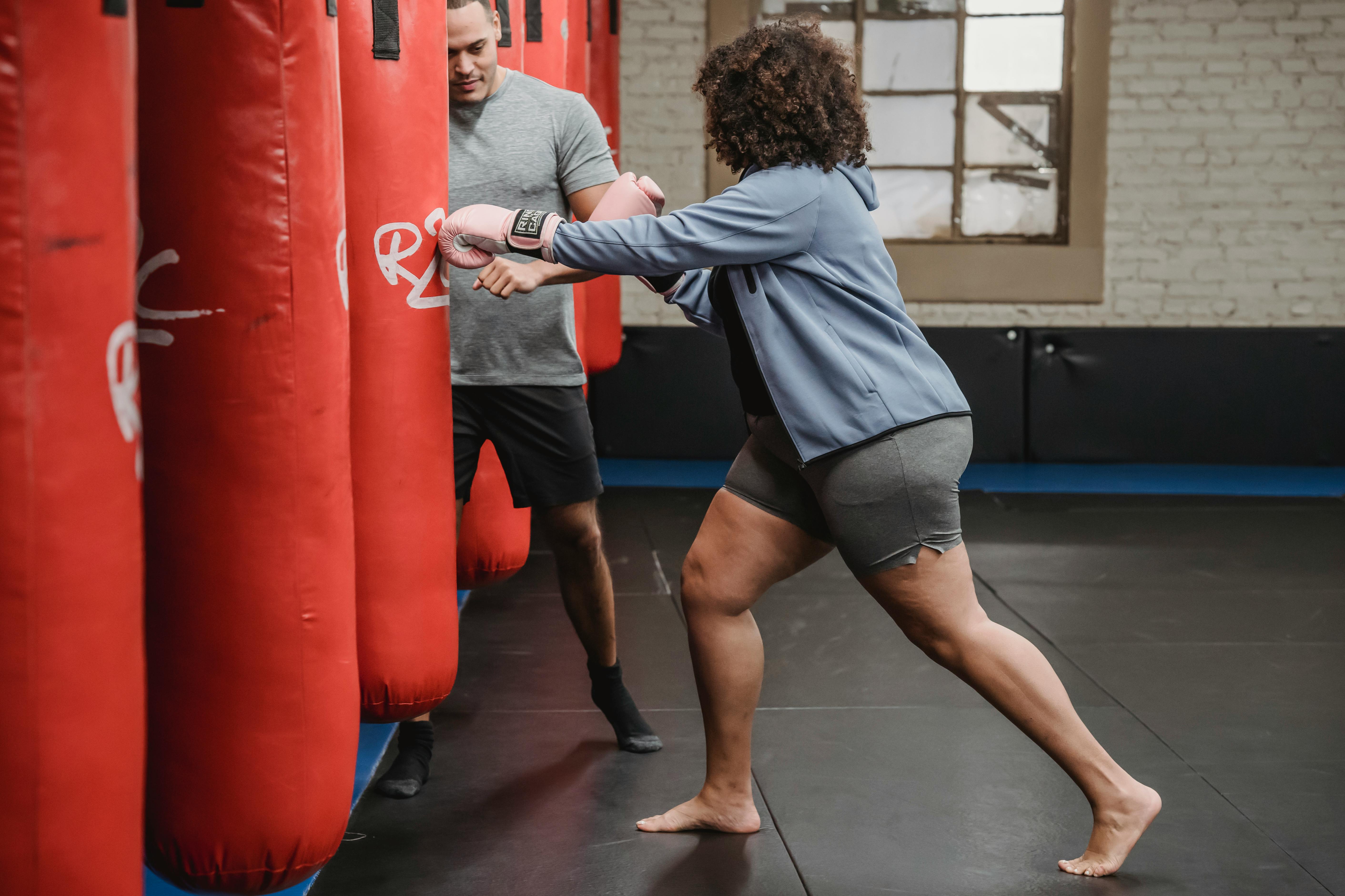 ethnic instructor practicing boxing with black woman