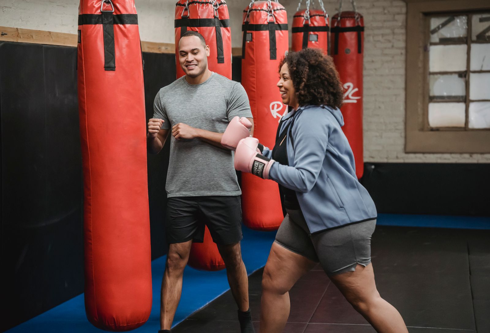 Allenatore e allieva sorridono durante un allenamento di boxe.