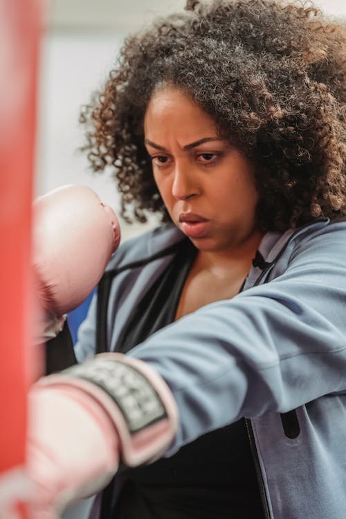Determined black woman in gloves at boxing training