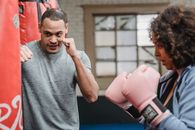 Concentrated ethnic male trainer with fists training with African American wearing boxing gloves in gym