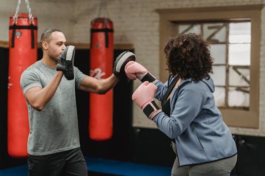 Man coaching woman in boxing session, emphasizing fitness and strength.