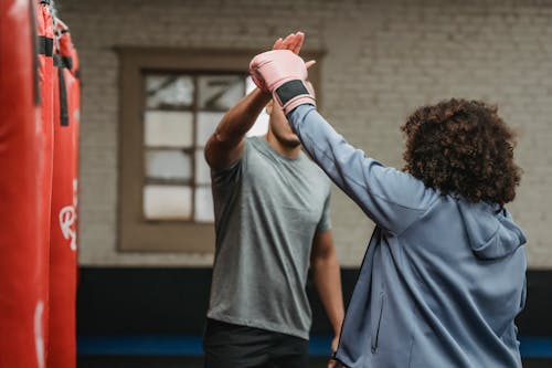 Anonymous male trainer explaining punching technique to female boxer in glove during training in gymnasium