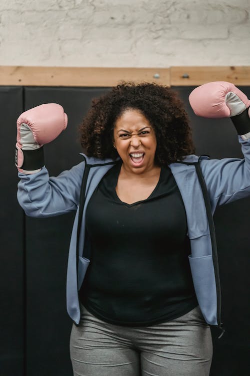 Aggressive black boxer in gloves in gym