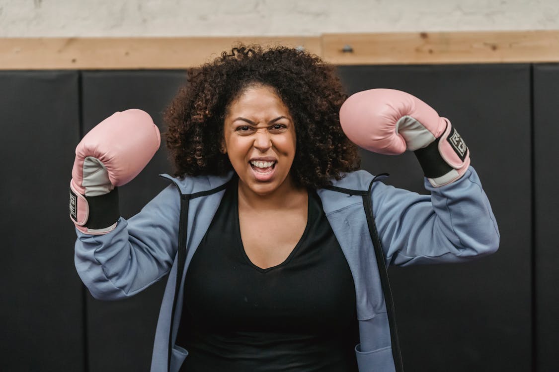 Free Excited young black sportswoman showing biceps after boxing training Stock Photo