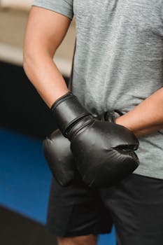 From above of crop unrecognizable male boxer in sportswear and protective gloves standing in ring before fight