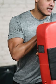 Focused male athlete training with a punching bag in the gym.