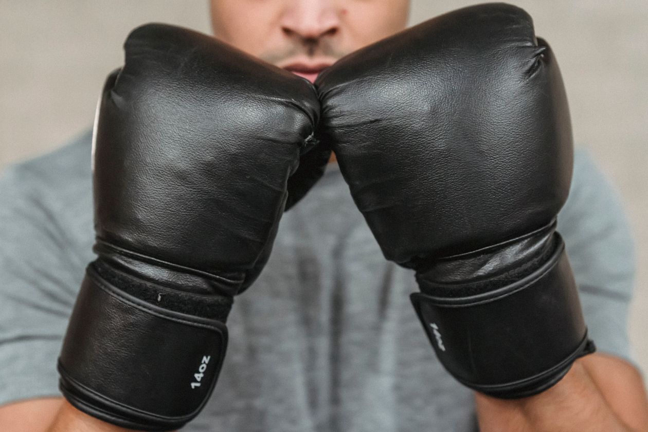 Primer plano de un boxeador con guantes negros en posición defensiva.