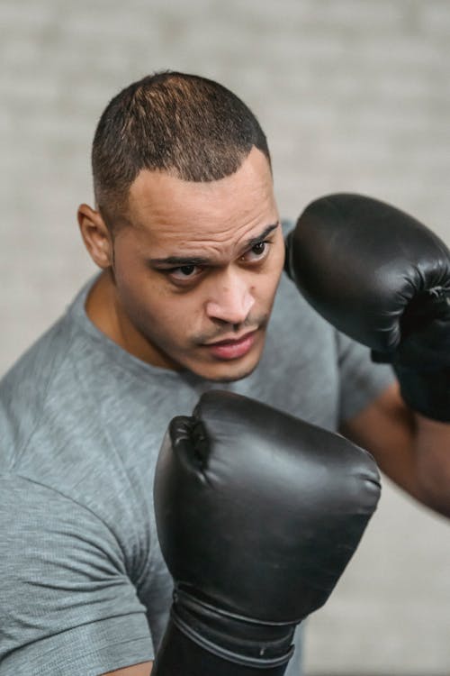 Confident young ethnic male fighter standing in boxing stance during training