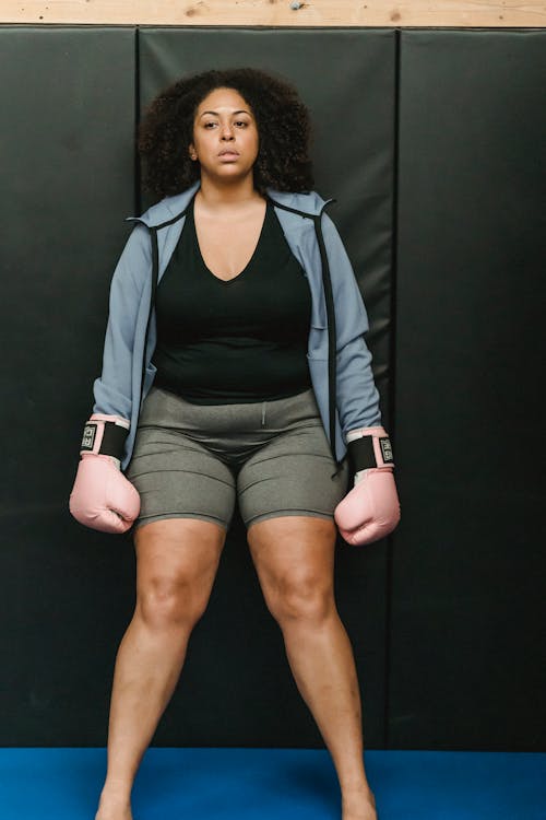 Determined young black female fighter standing in ring before boxing workout