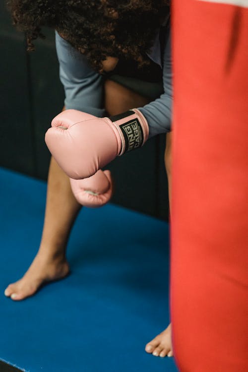 Anonymous tired ethnic female fighter resting in ring after boxing