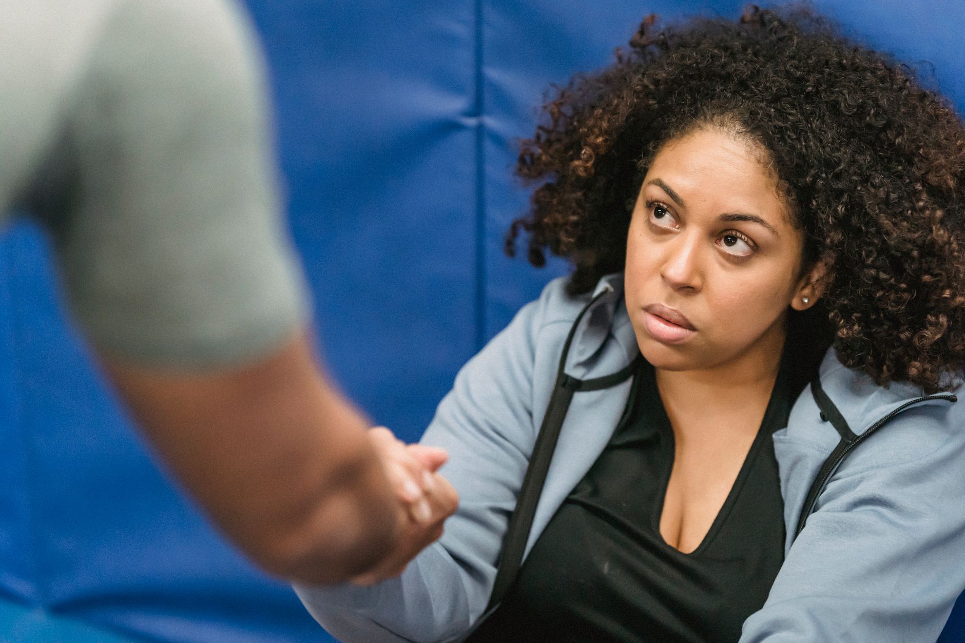 健身房 vs 居家訓練:哪個更適合你的健身需求? A determined woman receives motivational support in a gym setting, fostering teamwork and resilience.