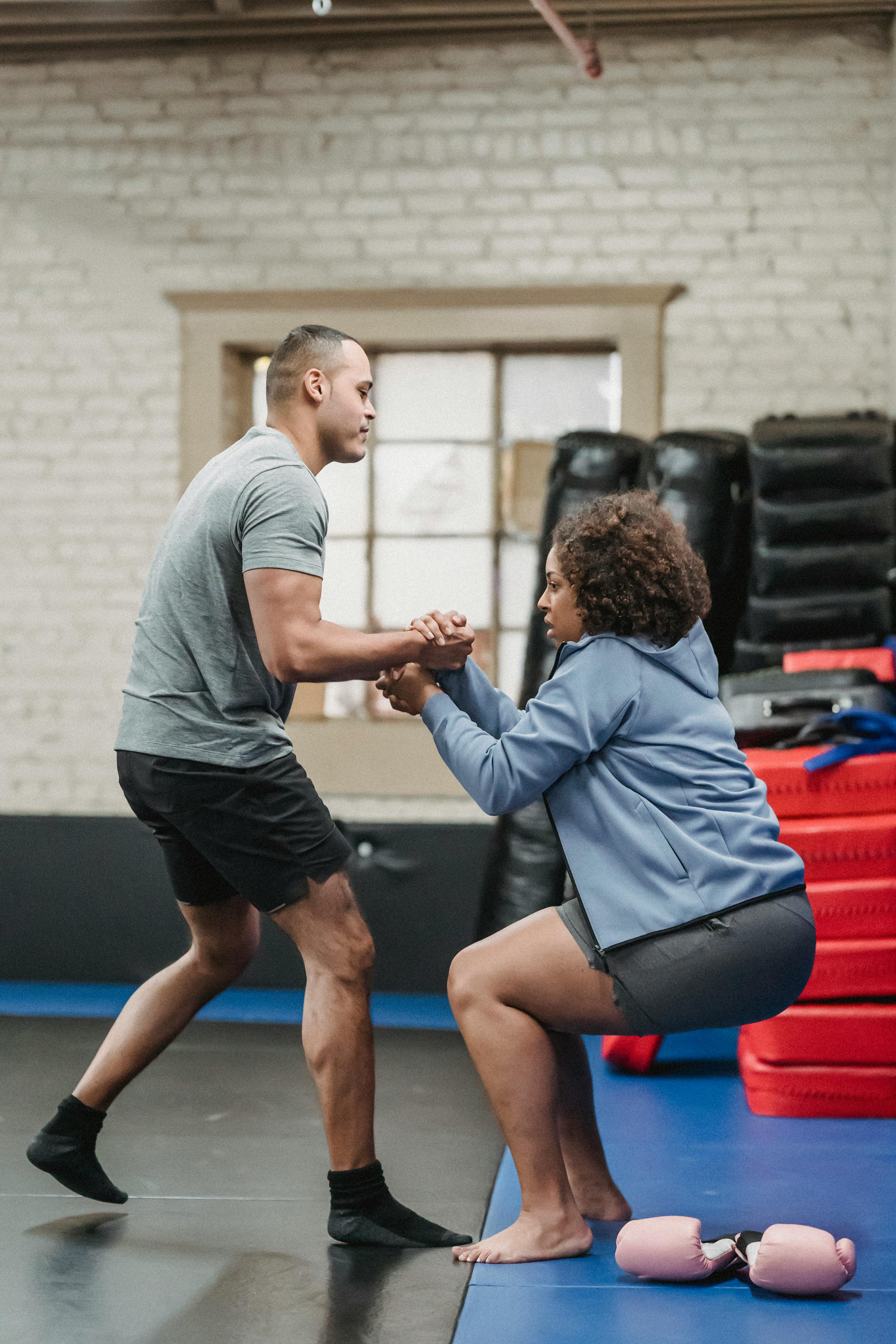 black trainer helping sportswoman to get up