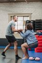 Black trainer helping sportswoman to get up