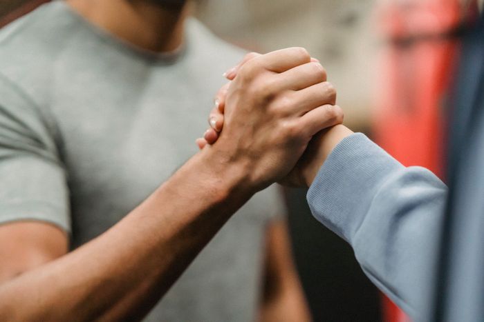 Close-up of a trainer and client clasping hands in a gym