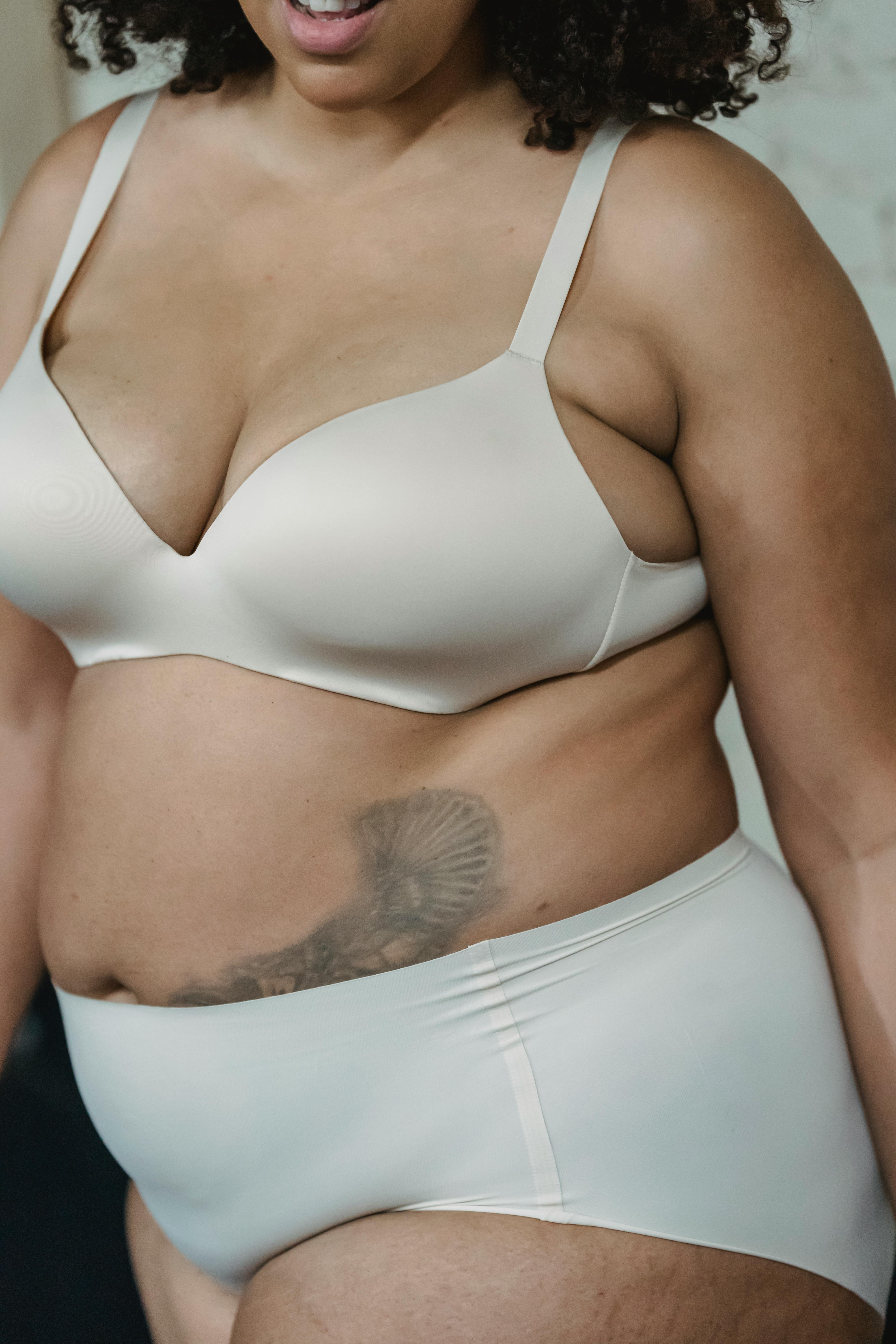 Crop unrecognizable black woman in bodysuit touching breast