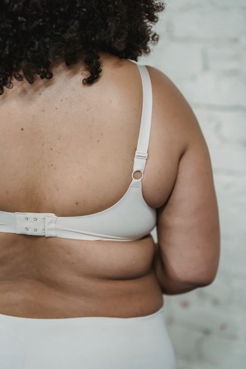 Free Back view of unrecognizable plus size female with curly hair wearing white underwear standing near white brick wall in room Stock Photo