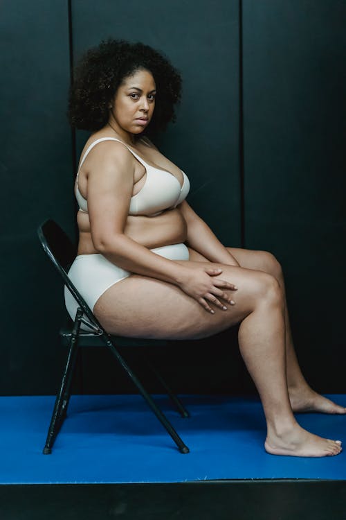 Plump black woman in underwear sitting in studio