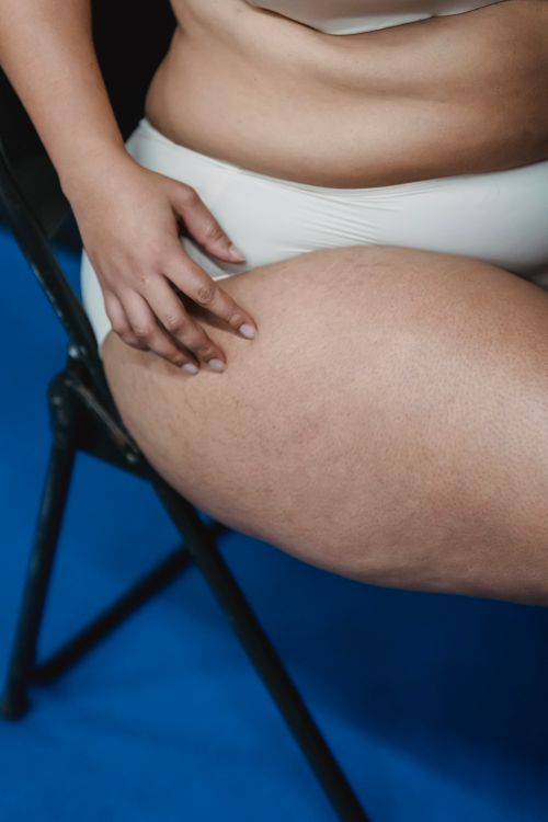 Free Side view of unrecognizable plus size female with stretches marks wearing panties sitting on chair on blue mat in room Stock Photo
