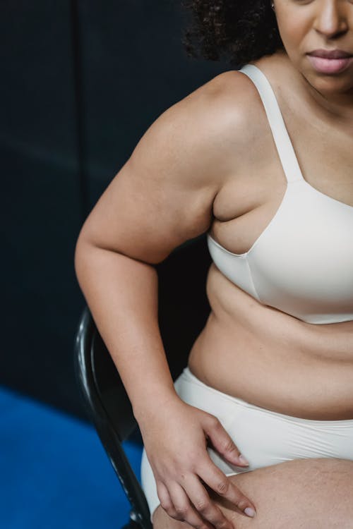 Donna In Reggiseno Bianco E Mutandine Bianche Che Si Siede Sulla Sedia In Pelle Nera