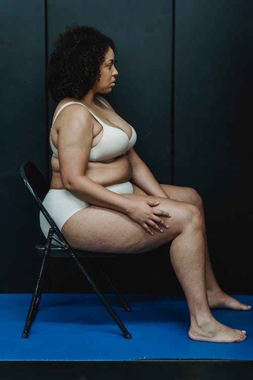 Serious plus size ethnic lady on chair near wall