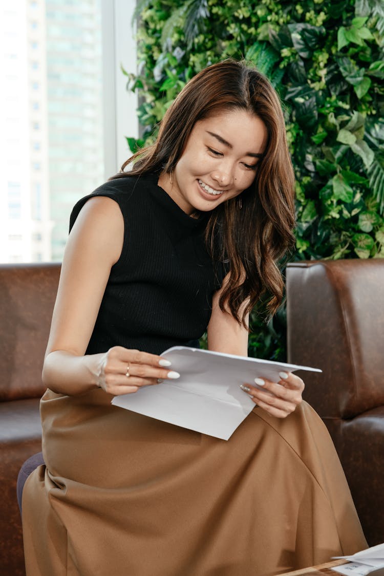 Smiling Asian Woman With Papers On Couch