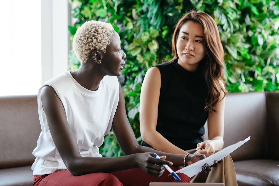 Free Diverse women talking about job while discussing contract and looking at each other in conference hall Stock Photo