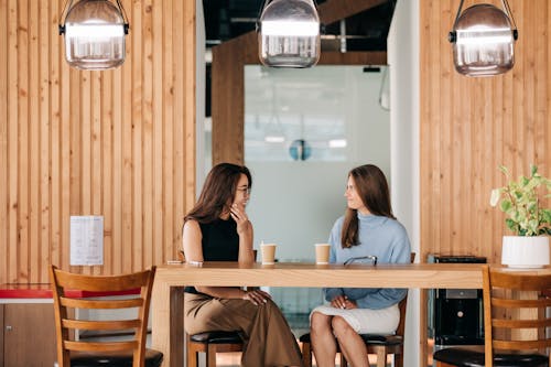Free Cheerful diverse friends talking at table with coffee in cafe Stock Photo