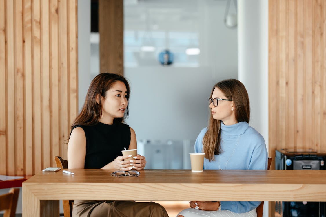 Free Diverse women talking during coffee break at table Stock Photo