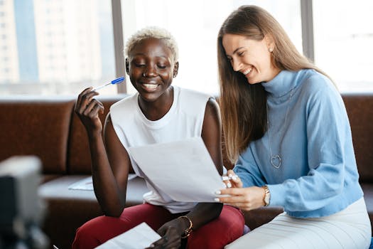 Positive diverse women checking information in document of agreement and smiling together in office