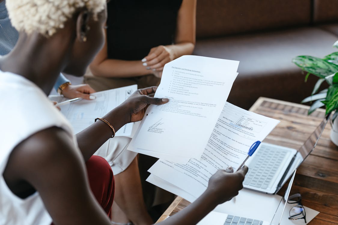 Free From above of crop anonymous African American female comparing data in papers at table of office Stock Photo