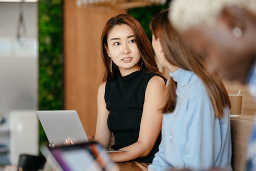 Free Asian woman discussing business plan with diverse colleagues Stock Photo