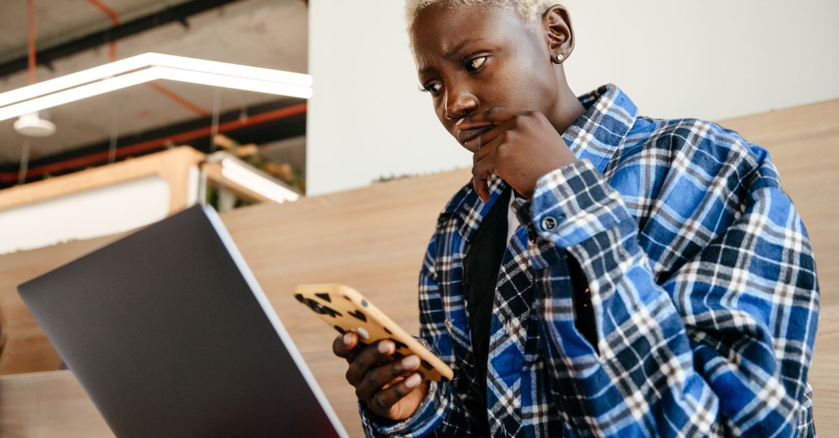 A person looking at a laptop with a thoughtful expression, not focused on the screen