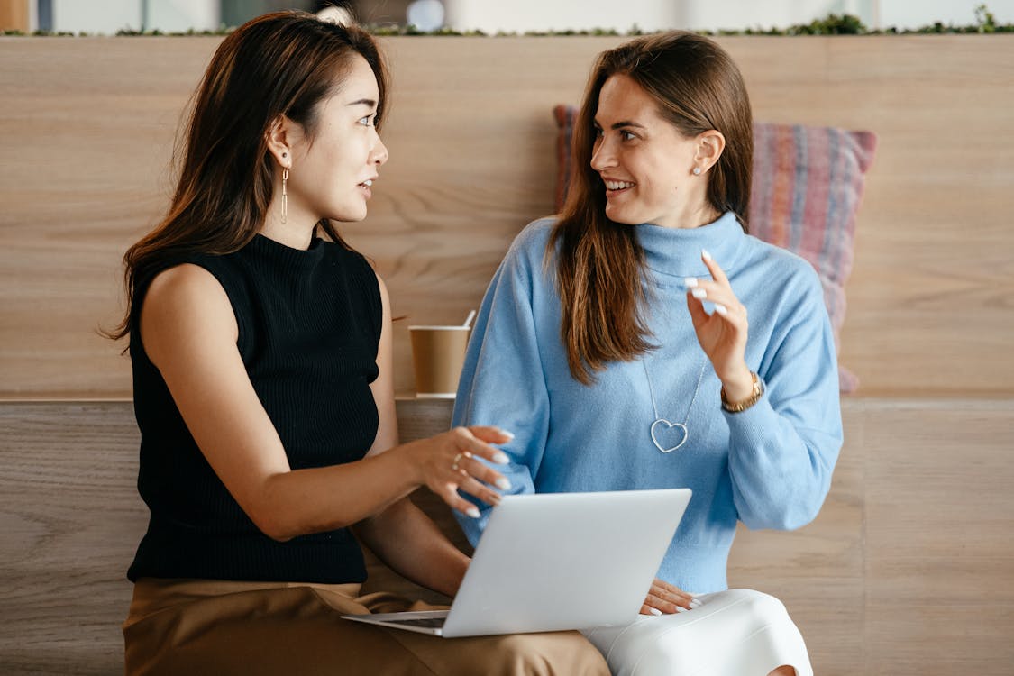 Free Young multiethnic business partners speaking about strategy of job while browsing netbook in contemporary workplace Stock Photo