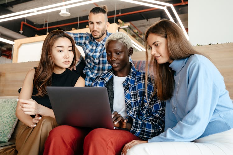 Multiethnic Women And Man Working On Project On Laptop