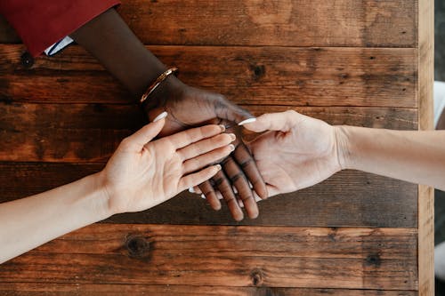Free Diverse women stacking hands on wooden table Stock Photo