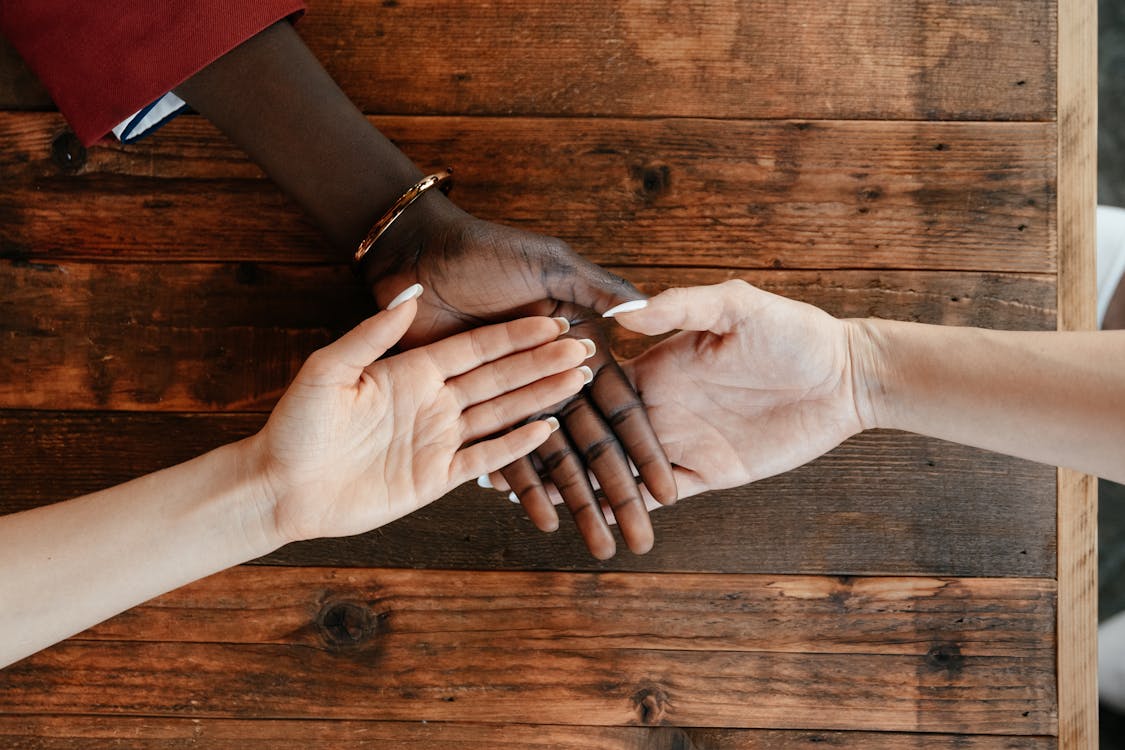 Photo by Alexander Suhorucov from Pexels: https://www.pexels.com/photo/diverse-women-stacking-hands-on-wooden-table-6457563/