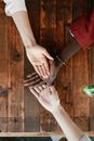 Top view of crop unrecognizable women stacking hands together on wooden surface in daytime